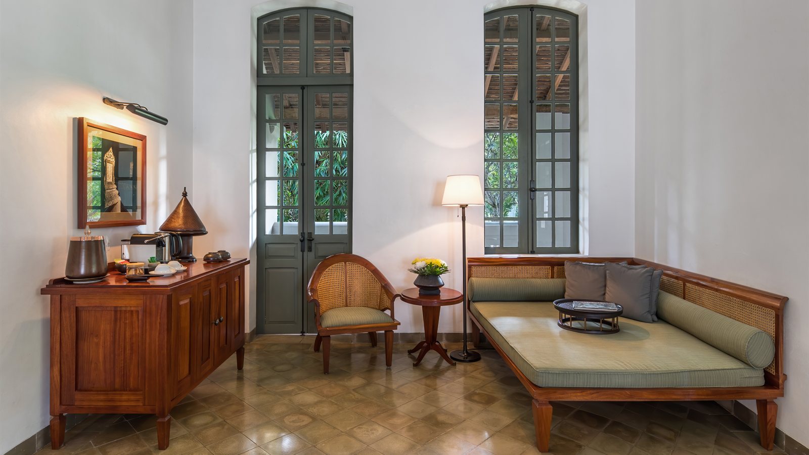 Quiet hotel lounge with tall shuttered doors and daybed